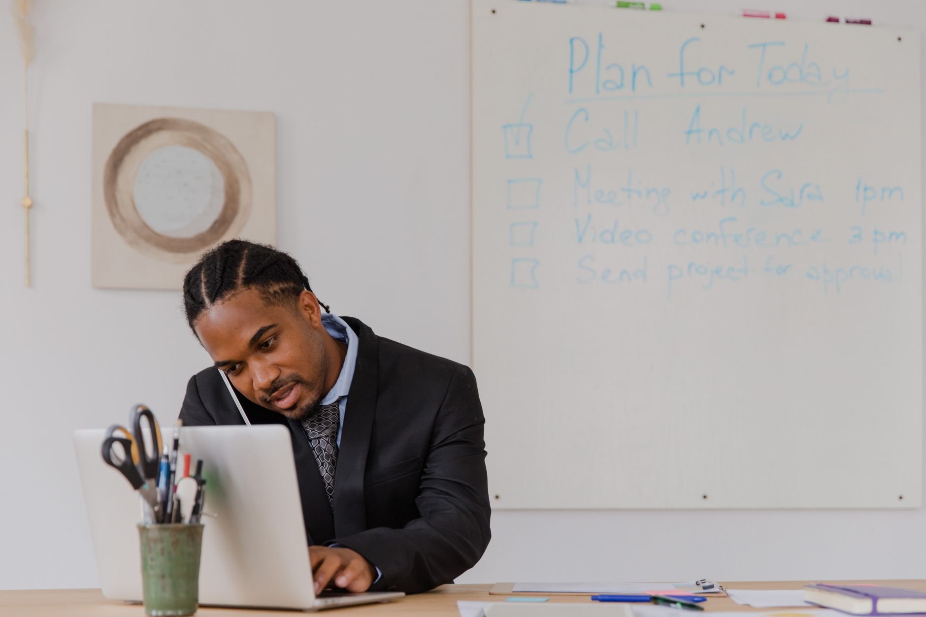 Business owner at desk managing phone calls and laptop work simultaneously